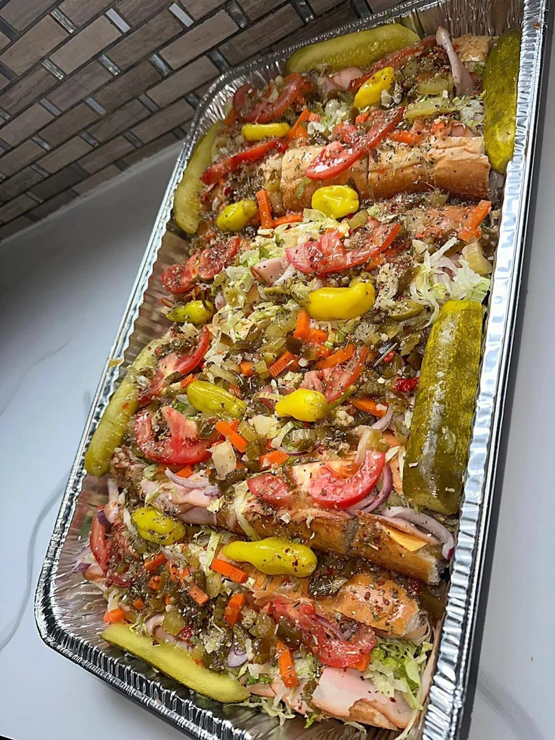 Party tray of loaded subs with giardiniera, tomatoes and pickles
